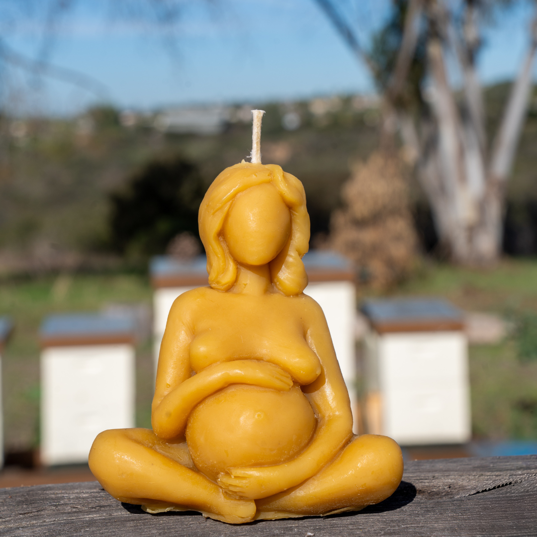 Beeswax candle shaped like a pregnant woman outdoors